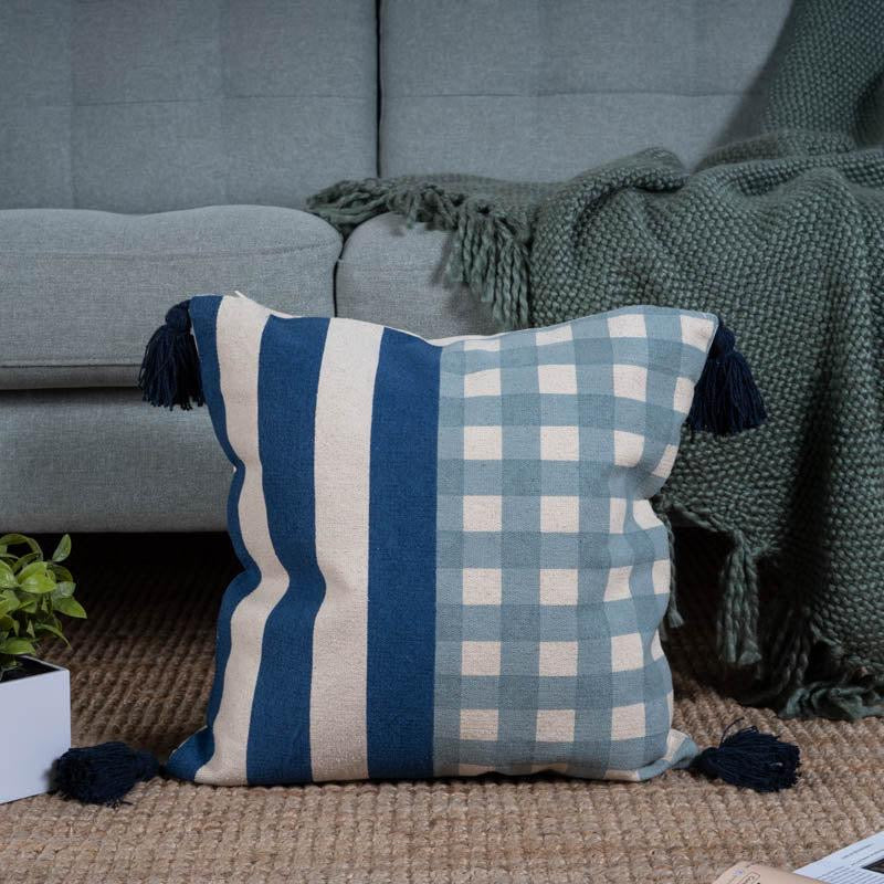 The Checks and Stripes Cushion, a square accent pillow with tassels and modern prints positioned in a living room you can buy online at Sukham Home, a sustainable furniture, kitchen & dining and home decor store in Kolkata, India.