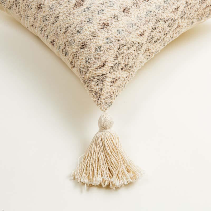 Corner closeup of the Mawsmai Cushion, a square accent pillow with tassels and ethnic prints you can buy online at Sukham Home, a sustainable furniture, kitchen & dining and home decor store in Kolkata, India.