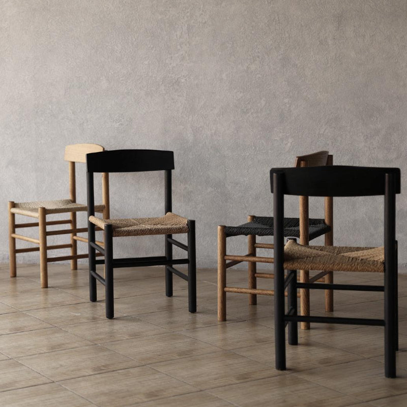 Set of People's Chairs with woven seats in a minimalistic room with a plant.