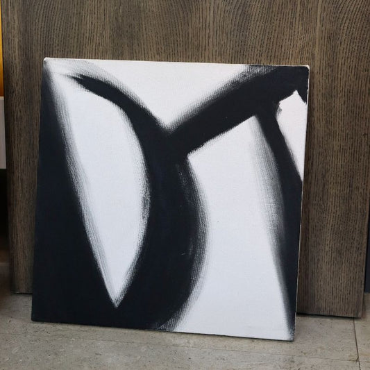 Placed against a wooden wall, The Black Stroke painting, a black and white canvas artwork you can buy online at Sukham Home, a sustainable furniture, kitchen & dining and home decor store in Kolkata, India