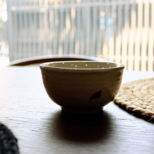 Against the light, silhouette of the Beige Ganga Small Bowl, an off-white and 24-karat gold ceramic small bowl you can buy online at Sukham Home, a sustainable furniture, gardening and home decor store in Kolkata, India