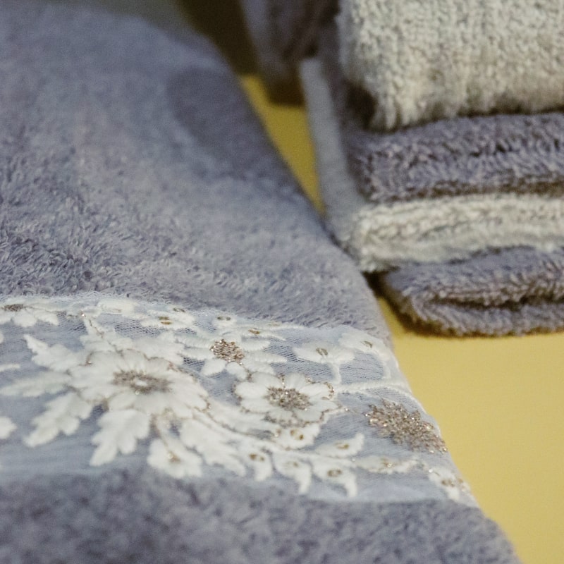 Close up of the hand towel and face towels from the Grey & Beige Silly-Cuddly, a set of 8 floral embroidered towels you can buy online at Sukham Home, a sustainable furniture, kitchen & dining and home decor store in Kolkata, India
