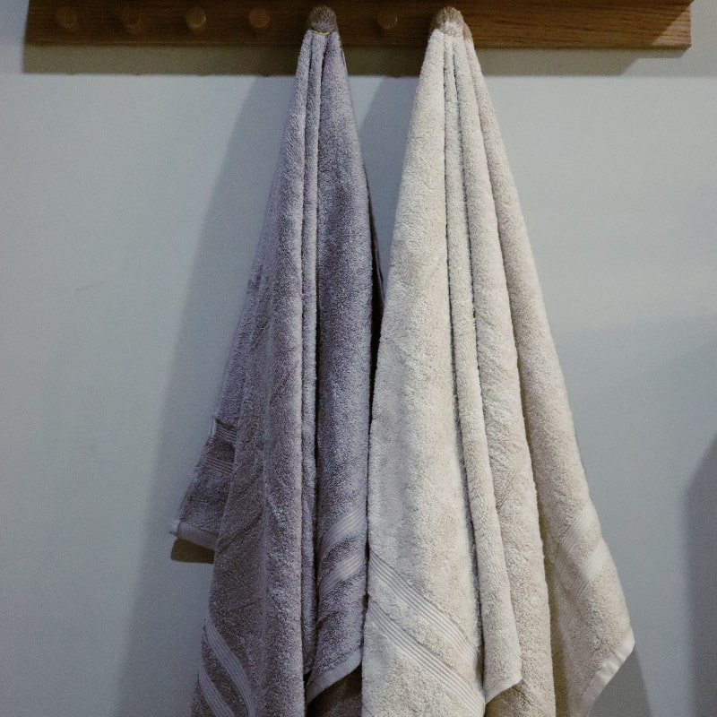 Hanging bath towels from the Grey & Beige Silly-Cuddly, a set of 8 floral embroidered towels you can buy online at Sukham Home, a sustainable furniture, kitchen & dining and home decor store in Kolkata, India