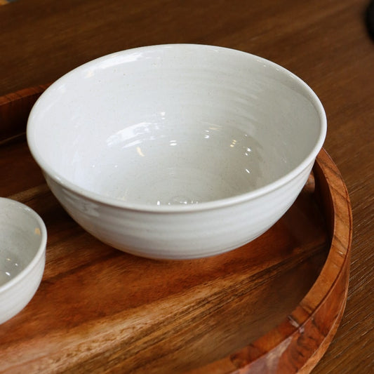 On a wooden tray, the Ivory Ganga Serving Bowl, a white and 24-karat gold ceramic serving big bowl you can buy online at Sukham Home, a sustainable furniture, gardening and home decor store in Kolkata, India