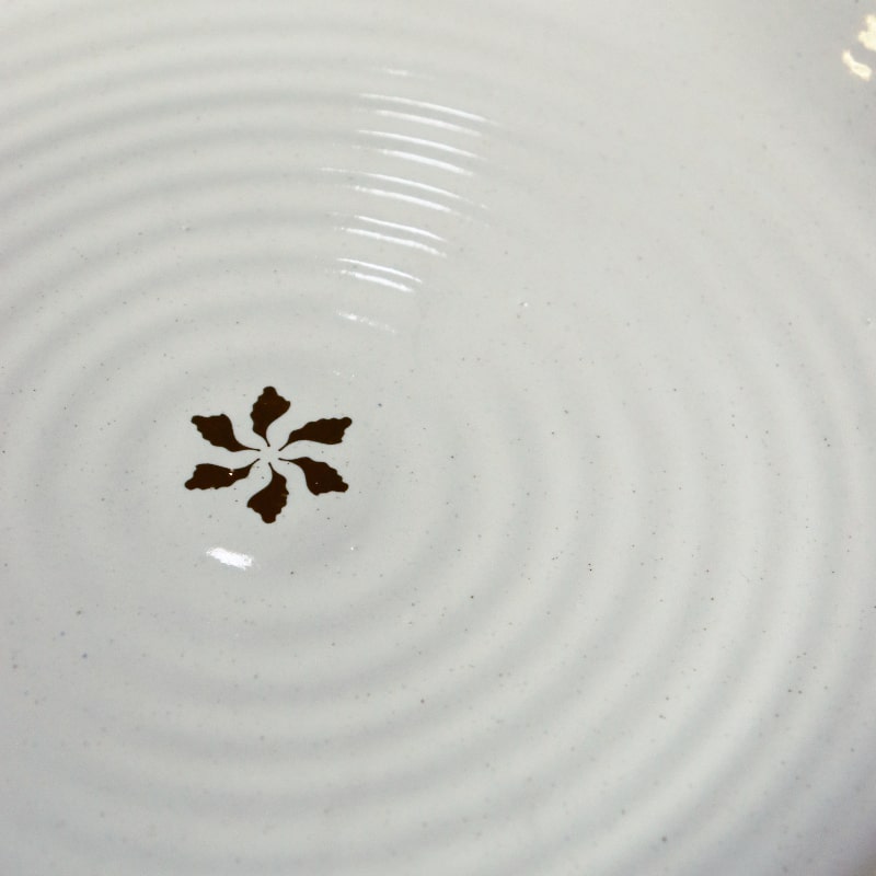 Close up of the gold flakes and ribbed design on the Ivory Ganga Dinner Plate, a pure white and 24-karat gold ceramic plate you can buy online at Sukham Home, a sustainable furniture, gardening and home decor store in Kolkata, India
