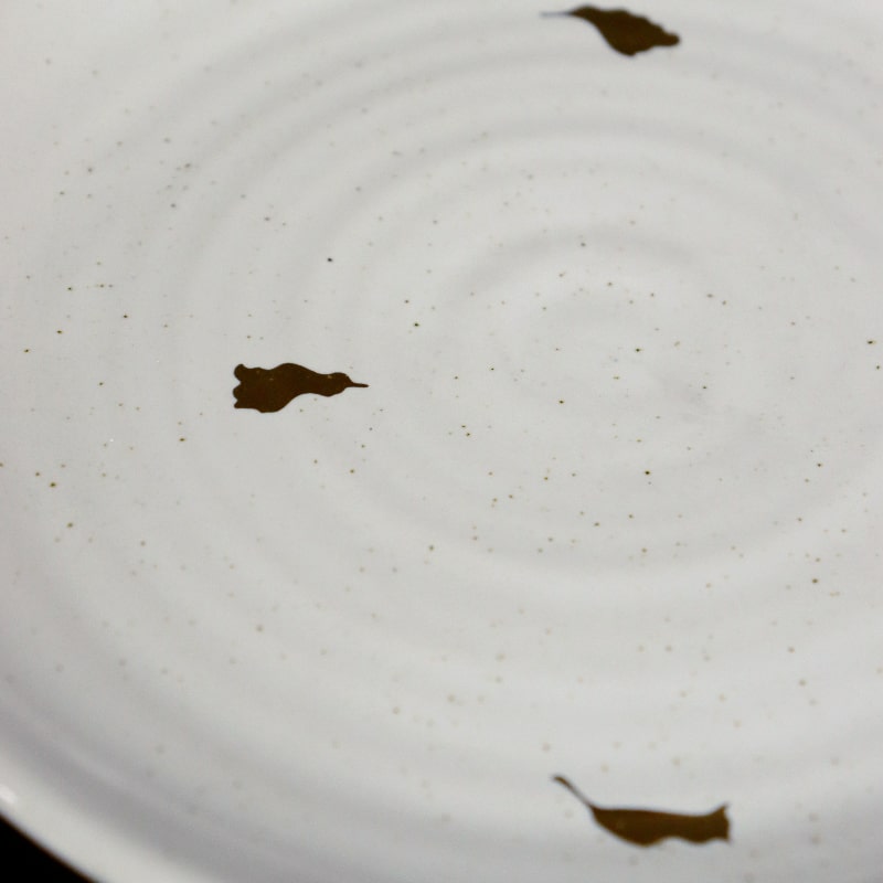 Close up of the ribbed texture and gold flakes on the Ivory Ganga Quarter Plate, a white and 24-karat gold ceramic small plate you can buy online at Sukham Home, a sustainable furniture, gardening and home decor store in Kolkata, India