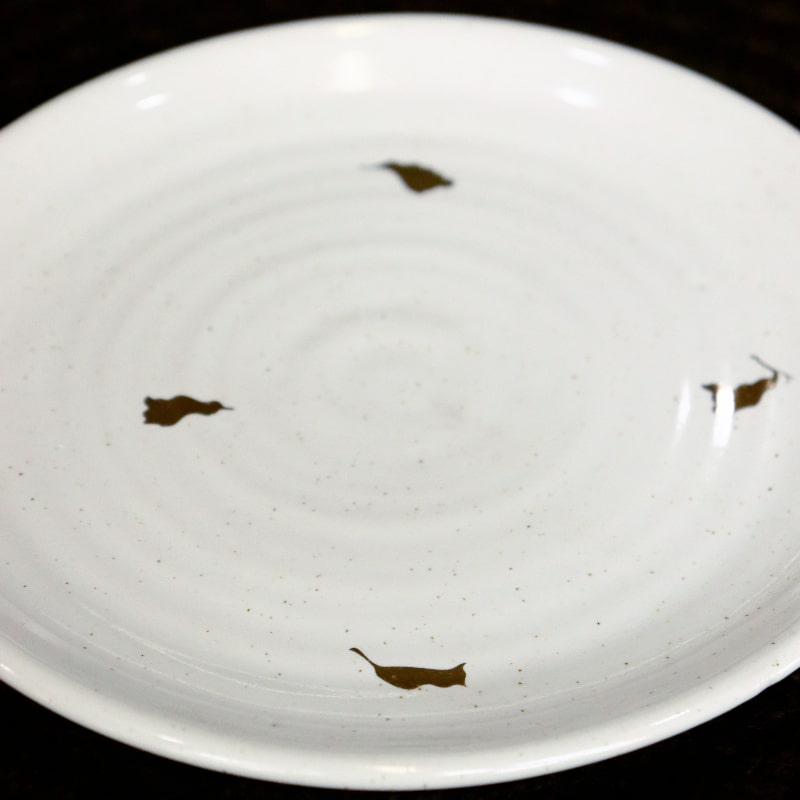 Tilted view of the Ivory Ganga Quarter Plate, a white and 24-karat gold ceramic small plate you can buy online at Sukham Home, a sustainable furniture, gardening and home decor store in Kolkata, India
