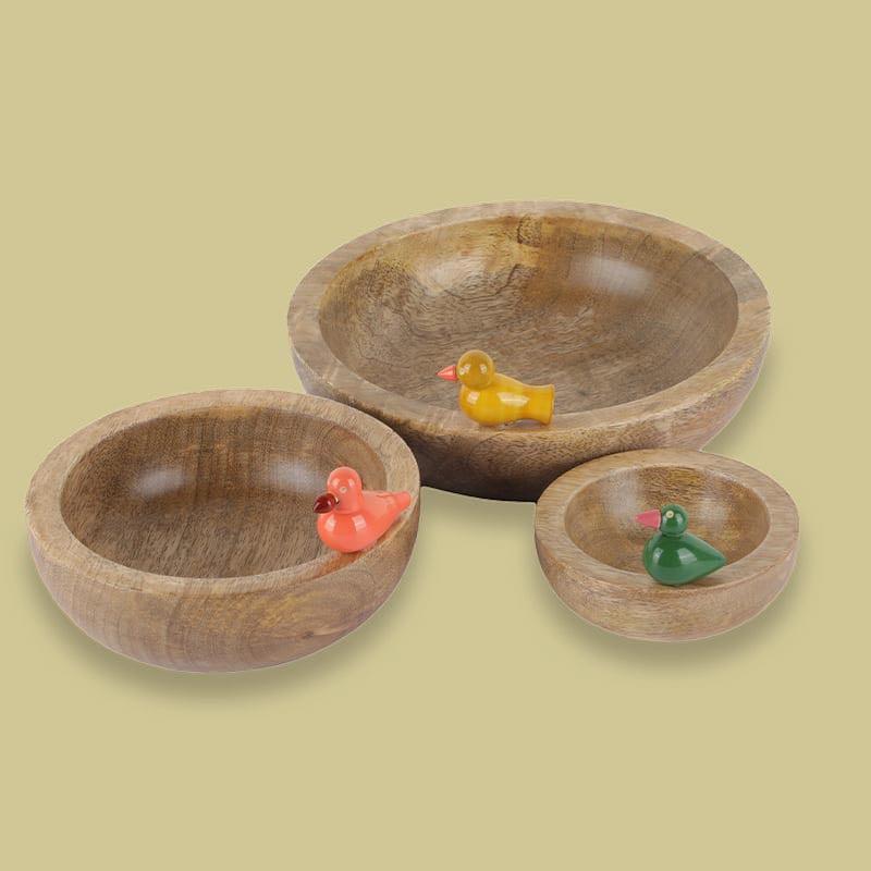 Against a yellow background, the Birds in Paradise Wooden Bowls, a set of 3 solid wood bowls with sculptures you can buy online at Sukham Home, a sustainable furniture, kitchen & dining and home decor store in Kolkata, India