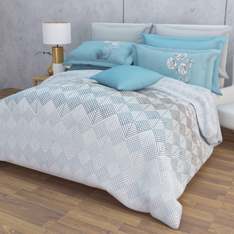 Arranged on a bed, the Hazy Blues, a printed blue geometric super king size bedsheet you can buy online at Sukham Home, a sustainable furniture, gardening and home decor store in Kolkata, India