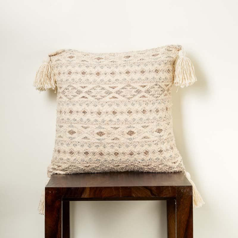  A piece of the Mawsmai Cushion, a square accent pillow with tassels and ethnic prints kept on a stool you can buy online at Sukham Home, a sustainable furniture, kitchen & dining and home decor store in Kolkata, India.