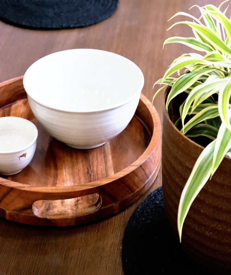 Wood round trays, ceramic dinnerware, solid oak wood dining tables & furniture, and planters made from recycled plastic you can buy online at Sukham Home, a sustainable furniture, gardening and home decor store in Kolkata, India