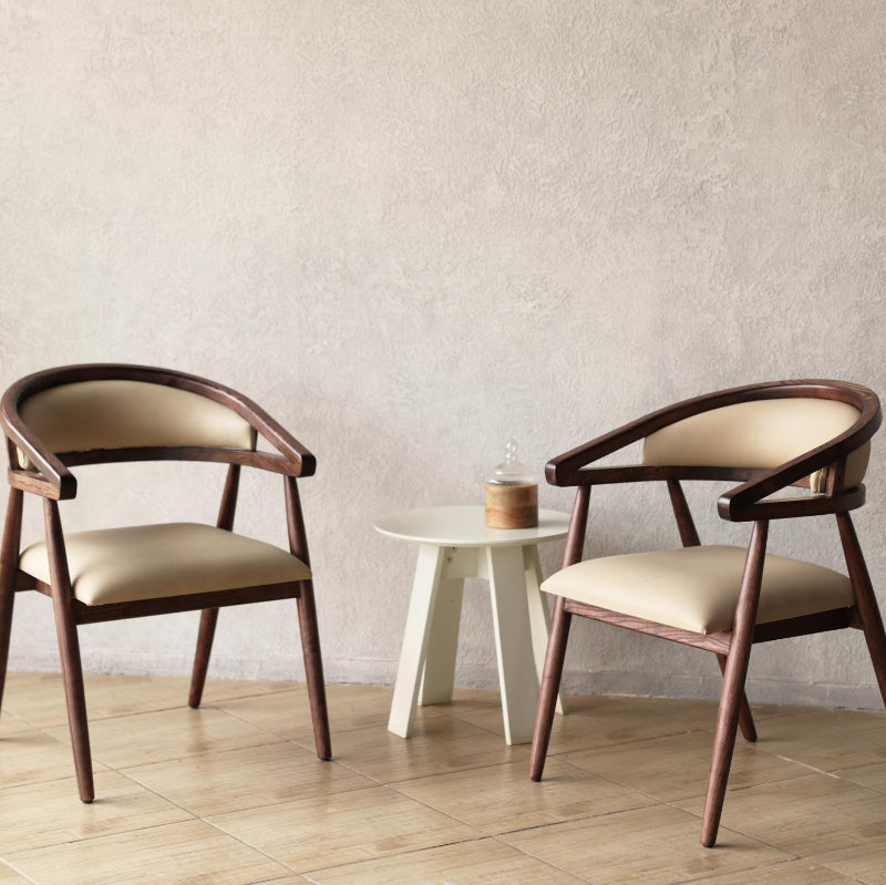 Two Pie Wooden Chairs with beige padded cushions in a minimalistic room.