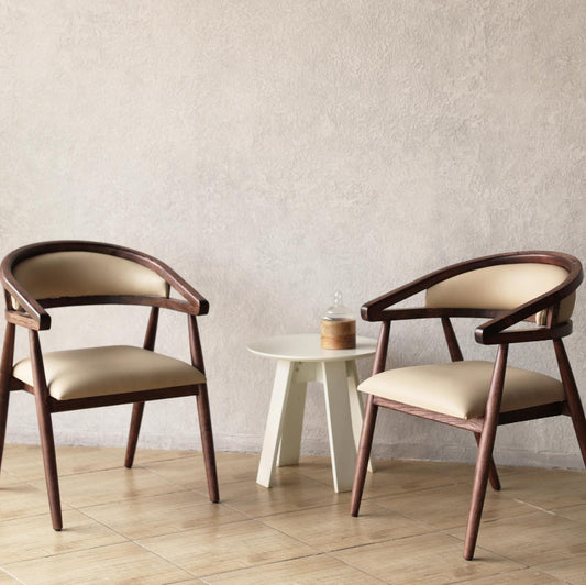 Two Pie Wooden Chairs with beige padded cushions in a minimalistic room.
