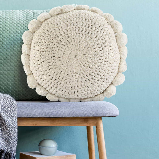 The Snowball Crochet Cushion, a round accent pillow with crochet and fluffy pom poms which you can buy online at Sukham Home, a sustainable furniture, kitchen & dining and home decor store in Kolkata, India.