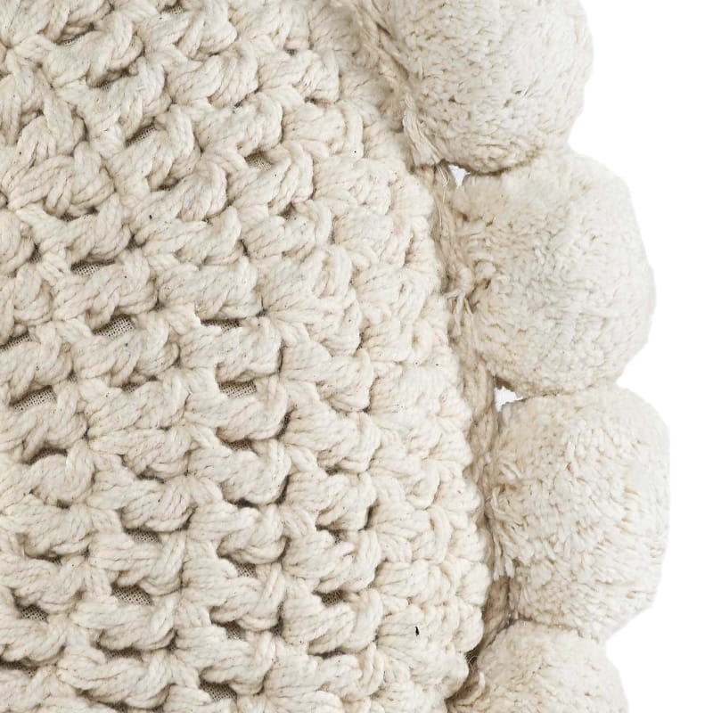 Closeup of the Snowball Crochet Cushion, a round accent pillow with crochet and fluffy pom poms which you can buy online at Sukham Home, a sustainable furniture, kitchen & dining and home decor store in Kolkata, India.