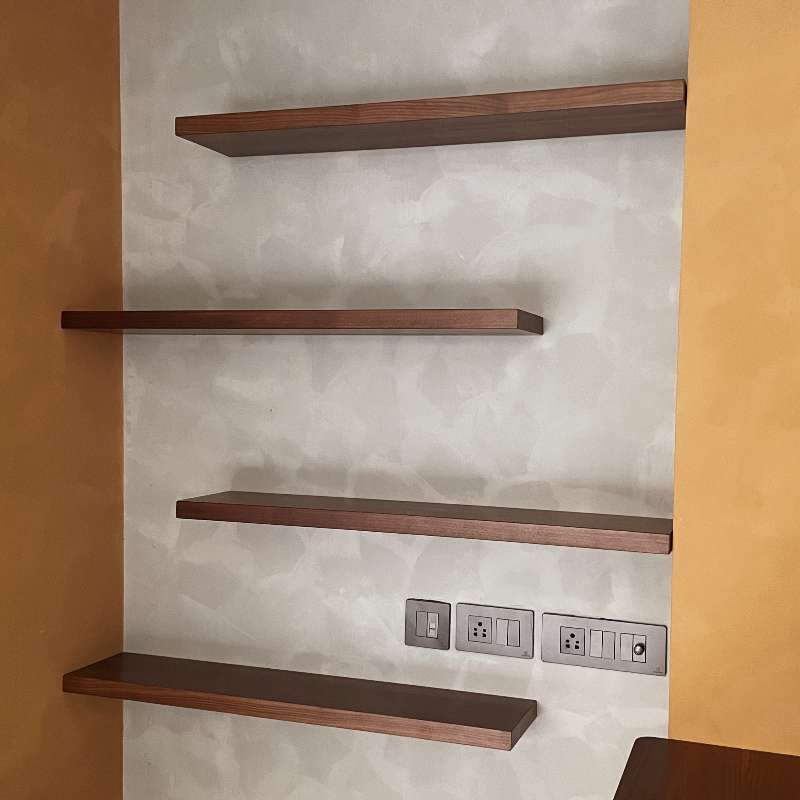 Against a grey wall, the Walnut Natural Float Shelf, a multipurpose wooden wall shelf and storage solution you can buy online at Sukham Home, a sustainable furniture, kitchen & dining and home decor store in Kolkata, India