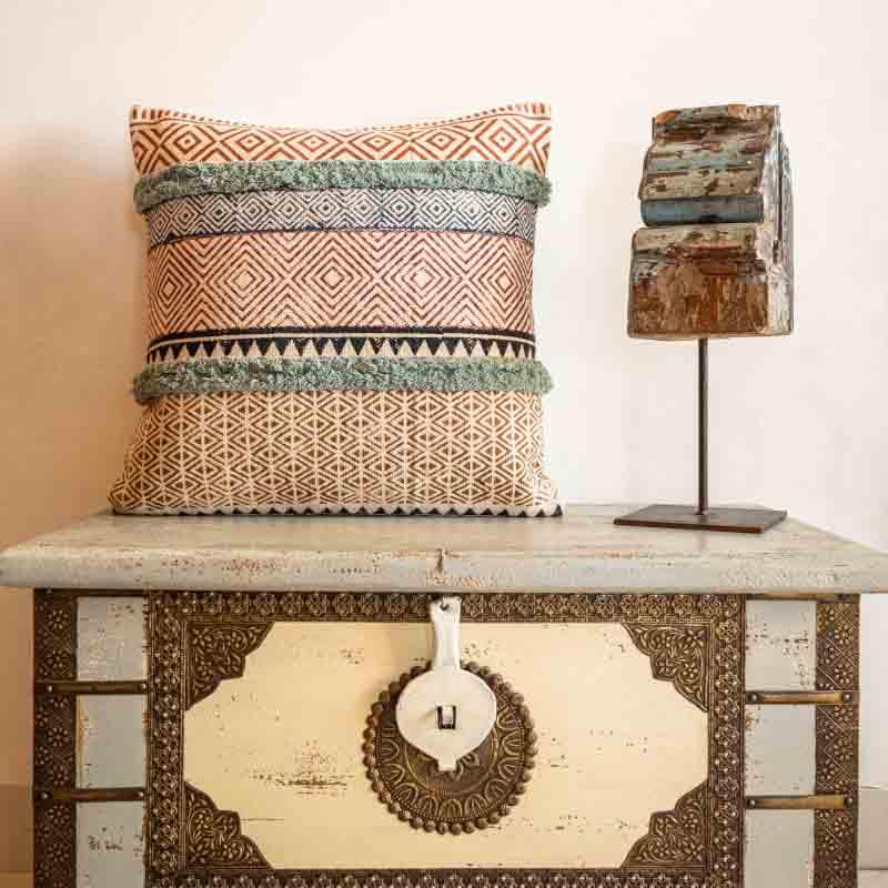 Placed on a chest, the Abstract Fantasy Cushion, a cotton handpainted and tufted accent pillow you can buy online at Sukham Home, a sustainable furniture, kitchen & dining and home decor store in Kolkata, India