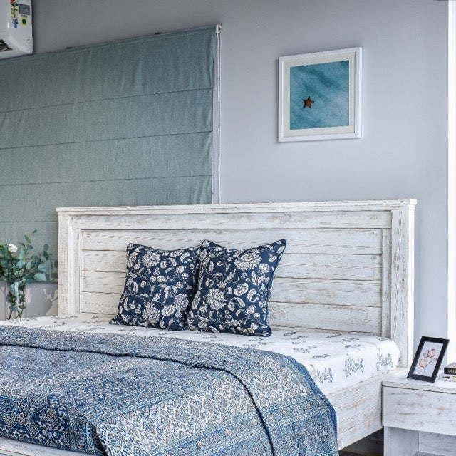 Set up with blue bedding, Archaic, a wooden white patina bed inspired by harbour and coastal style furniture you can buy online at Sukham Home, a sustainable furniture, kitchen & dining and home decor store in Kolkata, India