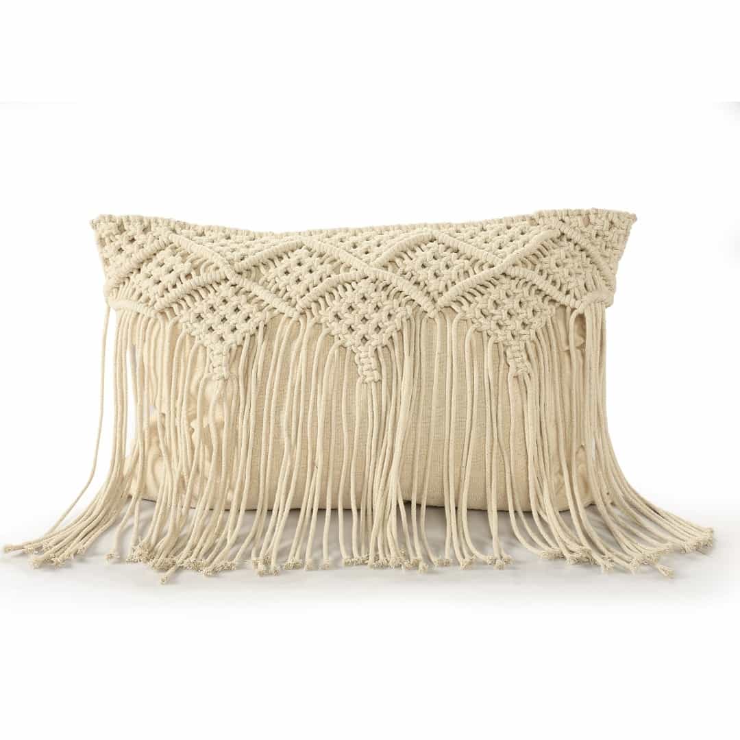 Against a white background, the Beige White Macrame Cushion with Fringes, a rectangle accent pillow you can buy online at Sukham Home, a sustainable furniture, kitchen & dining and home decor store in Kolkata, India