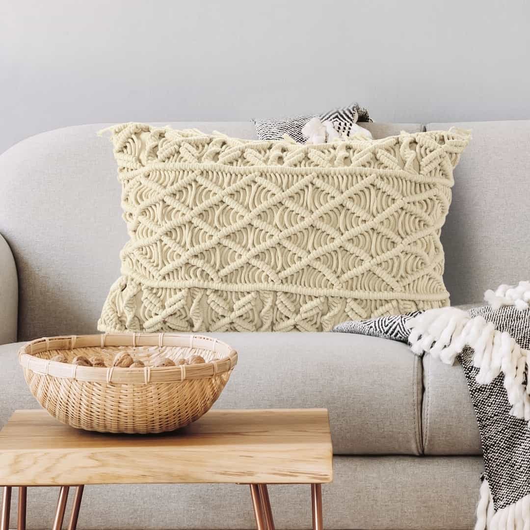 Arranged on a grey sofa, the Beige White Macrame Cushion, a rectangle accent pillow you can buy online at Sukham Home, a sustainable furniture, kitchen & dining and home decor store in Kolkata, India