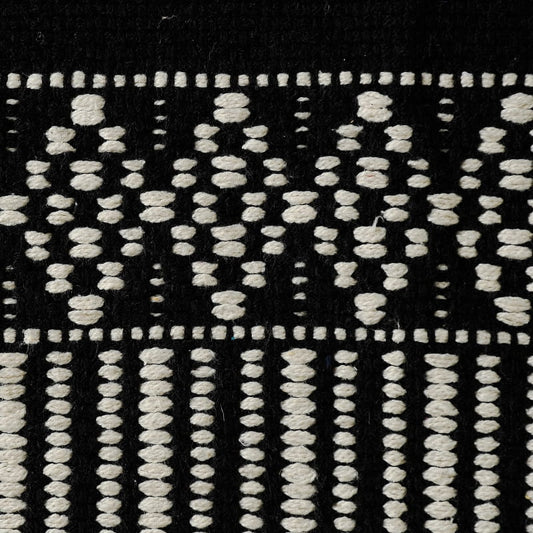 Close up of the weaving pattern on the Woven Black and White Rug, a rectangle cotton carpet in black & white you can buy online at Sukham Home, a sustainable furniture, kitchen & dining and home decor store in Kolkata, India