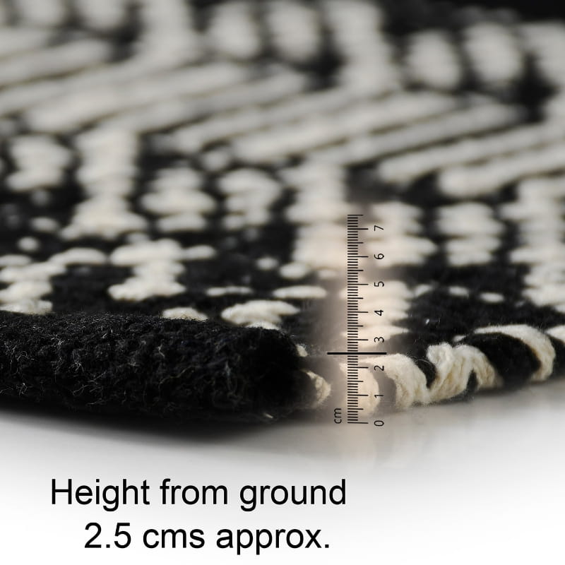 Close up of the corner of the Woven Black and White Rug, a rectangle cotton carpet in black & white you can buy online at Sukham Home, a sustainable furniture, kitchen & dining and home decor store in Kolkata, India