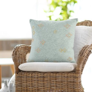 Placed on a chair, the Minimalist Threaded Cushion, a square blue embroidered accent pillow available at Sukham Home, a sustainable furniture, kitchen & dining and home decor store in Kolkata, India