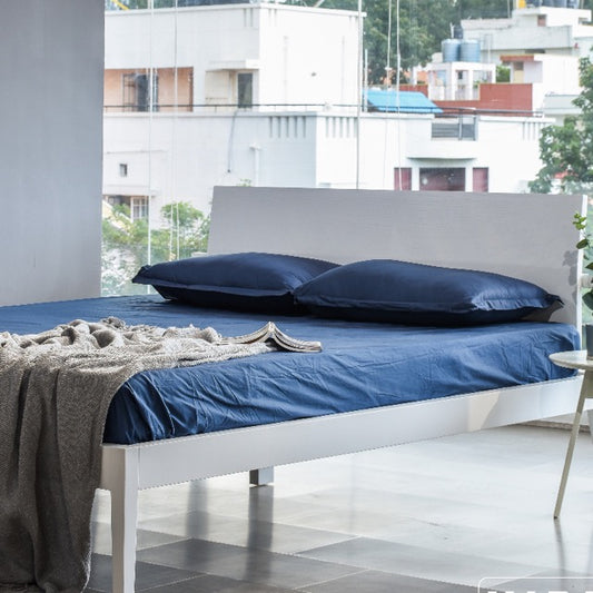 The White PU Calm, a wooden bed with a slanted headboard you can buy online at Sukham Home, a sustainable furniture, kitchen & dining and home decor store in Kolkata, India