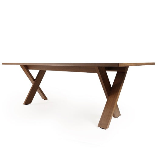 Against a white background, side view of the Walnut Natural Cross, a wooden long dining table you can buy online at Sukham Home, a sustainable furniture, kitchen & dining and home decor store in Kolkata, India