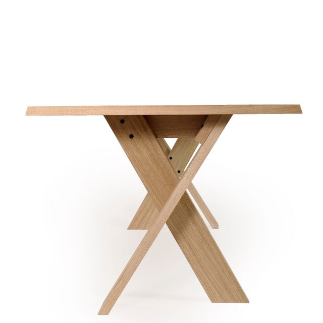 Against a white background, close up of the legs of the Oak Natural Cross, a wooden long dining table you can buy online at Sukham Home, a sustainable furniture, kitchen & dining and home decor store in Kolkata, India