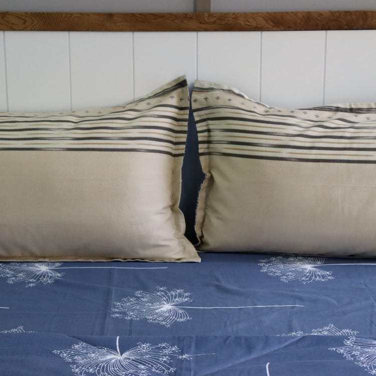 Displaying the reverse beige side of the pillowcases of the Dandelion Blue-Grey Printed Bedsheet, a blue and beige king size cotton bedsheet you can buy online at Sukham Home, a sustainable furniture, gardening and home decor store in Kolkata, India