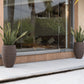 Placed outdoors, two Dark Brown Dual Tone Wood Rib High, a round tall textured luxury planter made from FRP you can buy online at Sukham Home, a sustainable furniture, gardening and home decor store in Kolkata, India