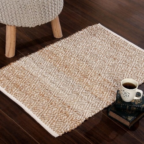 On a wooden floor, the Handwoven Jute Rug with Diamond Design Weaves, a small rectangle jute and white cotton carpet you can buy online at Sukham Home, a sustainable furniture, kitchen & dining and home decor store in Kolkata, India