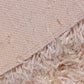 The bottom side of the Dori Shag Rug, a rectangle shaggy cotton carpet in pale pink you can buy online at Sukham Home, a sustainable furniture, kitchen & dining and home decor store in Kolkata, India