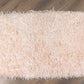 On a wood floor, the Dori Shag Rug, a rectangle shaggy cotton carpet in pale pink you can buy online at Sukham Home, a sustainable furniture, kitchen & dining and home decor store in Kolkata, India