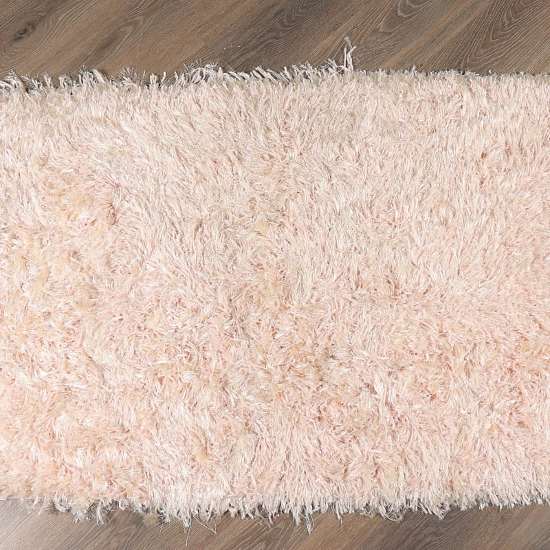 On a wood floor, the Dori Shag Rug, a rectangle shaggy cotton carpet in pale pink you can buy online at Sukham Home, a sustainable furniture, kitchen & dining and home decor store in Kolkata, India