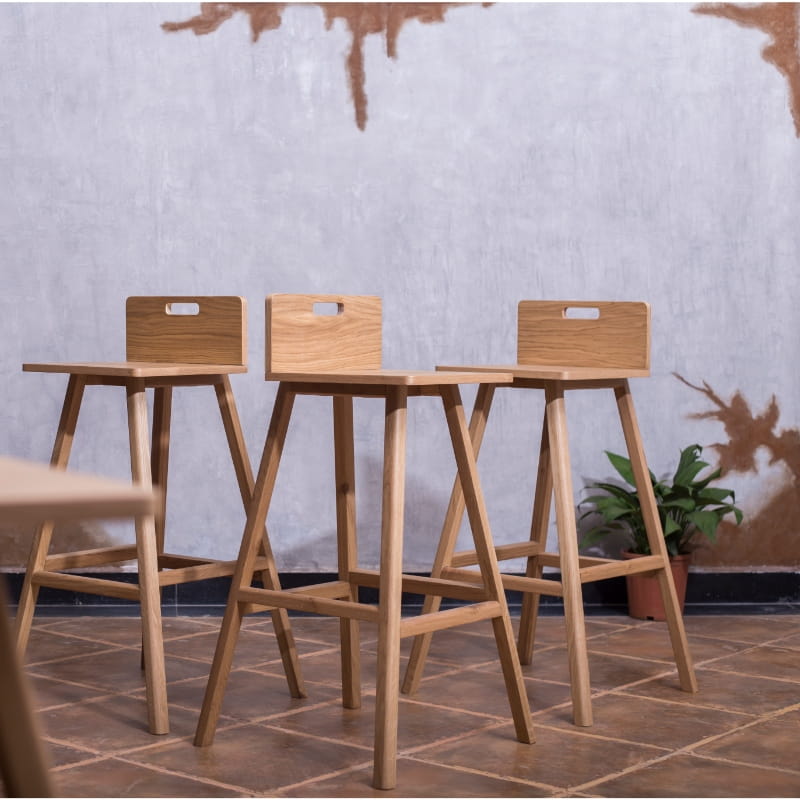 From a distance, three Oak Natural Flamingo Bar Stool, a solid wood high bar chair you can buy online at Sukham Home, a sustainable furniture and home decor store in Kolkata, India