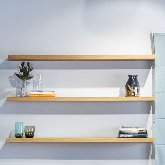 Against a blue wall, the Oak Natural Float Shelf, a multipurpose wooden wall shelf and storage solution you can buy online at Sukham Home, a sustainable furniture, kitchen & dining and home decor store in Kolkata, India