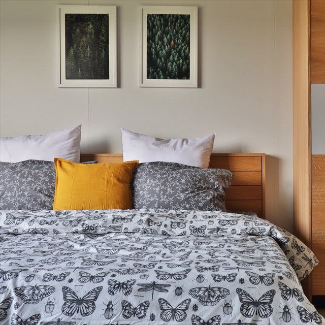 Arranged with black and white patterned sheets, the Fred, a wooden bed with a wood slatted framed headboard you can buy online at Sukham Home, a sustainable furniture, kitchen & dining and home decor store in Kolkata, India