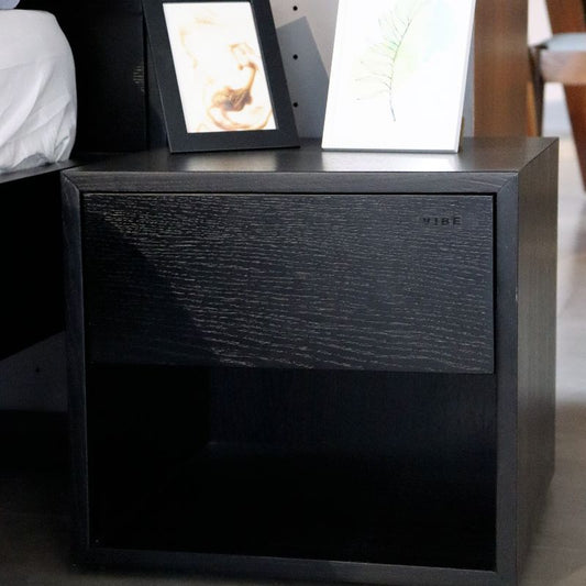 Side view of the Ash Charcoal Fred, a wooden bedside table with a drawer and cubby storage you can buy online at Sukham Home, a sustainable furniture, kitchen & dining and home decor store in Kolkata, India