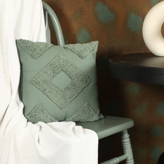 Placed on a green chair, the Green Loop Tufted Cushion, a square green accent pillow available at Sukham Home, a sustainable furniture, kitchen & dining and home decor store in Kolkata, India