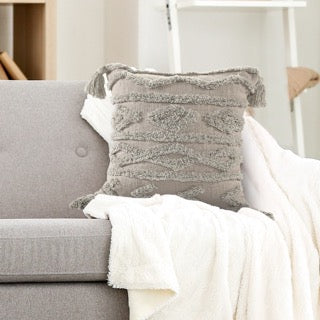 Placed on a sofa, the Grey Diamond Tufted Cushion, a square grey accent pillow available at Sukham Home, a sustainable furniture, kitchen & dining and home decor store in Kolkata, India