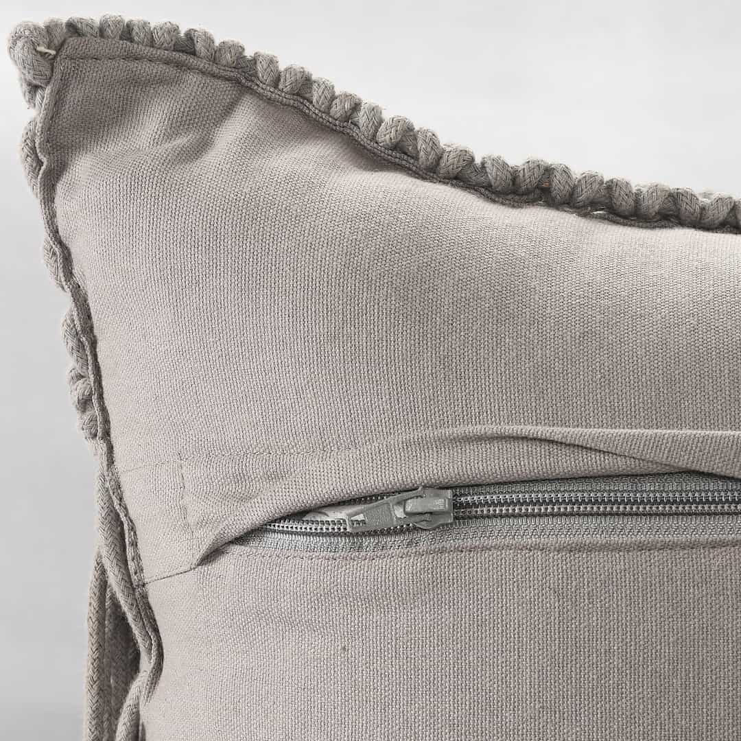 Close up of the zip of the Grey Macrame Cushion with Fringes, a rectangle accent pillow you can buy online at Sukham Home, a sustainable furniture, kitchen & dining and home decor store in Kolkata, India