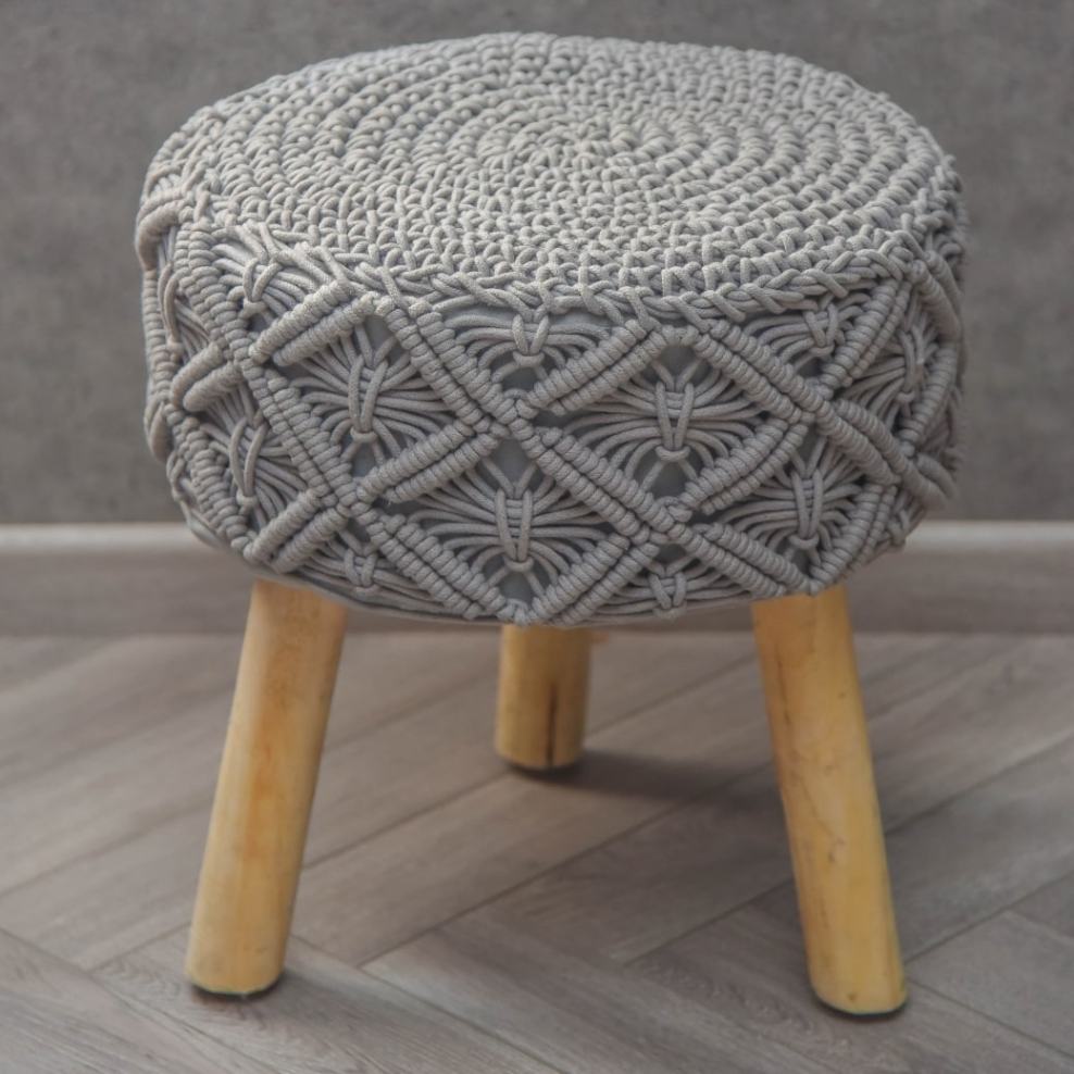 Placed on a wooden floor, the Grey Macrame Stool, a grey ottoman made from cotton and mango wood, available at Sukham Home, a sustainable furniture, kitchen & dining and home decor store in Kolkata, India