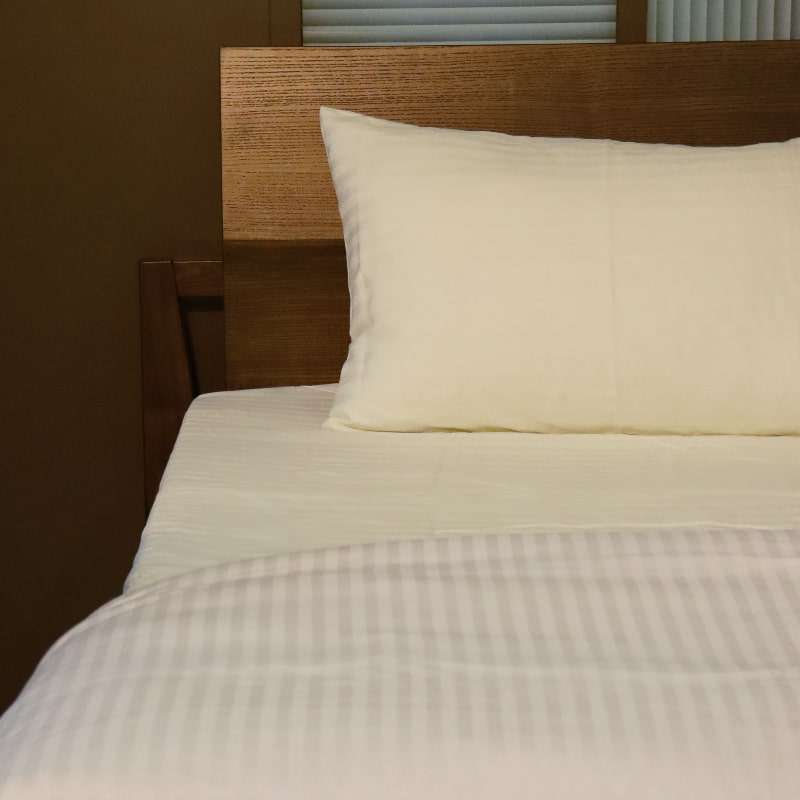 One pillowcase and sheet of the Ivory Sateen Striped Bedsheet, a cream king and queen size cotton bedsheet you can buy online at Sukham Home, a sustainable furniture, gardening and home decor store in Kolkata, India