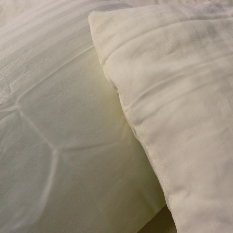 Close up of the pillowcases of the Ivory Sateen Striped Bedsheet, a cream king and queen size cotton bedsheet you can buy online at Sukham Home, a sustainable furniture, gardening and home decor store in Kolkata, India