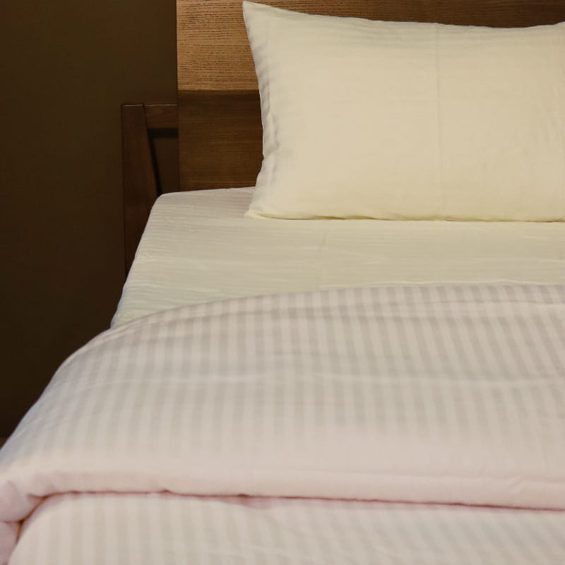 One pillow cover and duvet of the Ivory Striped Egyptian Cotton Duvet Cover, a white king size duvet cover you can buy online at Sukham Home, a sustainable furniture, gardening and home decor store in Kolkata, India