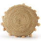 Against a white background, the Jute Round Floor Cushion, a circular braided accent pillow with pom poms, available at Sukham Home, a sustainable furniture, kitchen & dining and home decor store in Kolkata, India