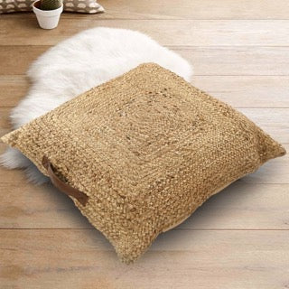 Against a wooden floor, the Jute Square Floor Cushion, a square braided accent pillow, available at Sukham Home, a sustainable furniture, kitchen & dining and home decor store in Kolkata, India