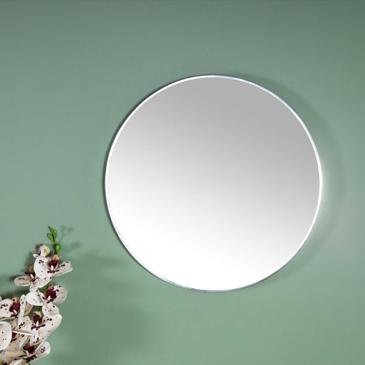Against a green background, the big Luna, a frameless round mirror you can buy online at Sukham Home, a sustainable furniture, kitchen & dining and home decor store in Kolkata, India